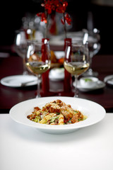 Vegetable salad with roasted meat, glass of white wine in background, shallow depth of field