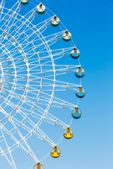 Amusement park ferris wheel in the blue sky