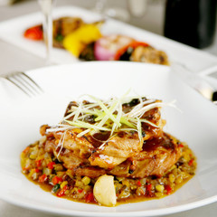 Grilled meat served in a plate with vegetables in sauce, shallow depth of field