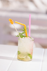 A jar of mojito cocktail with ice and a straw  at a beach bar