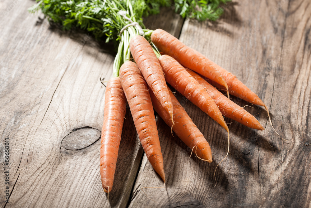 Wall mural fresh carrots on wooden background