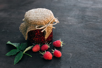 Raspberry jam in a jar on the wooden table