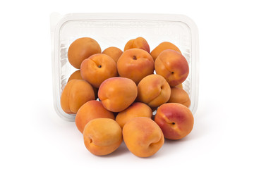 Box or punnet and spilled fresh ripe organic apricots isolated on white background