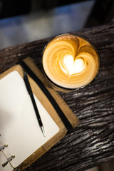 Heart shape latte art hot coffee with leather cover notebook
