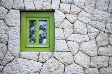 Fototapeta na wymiar Green wooden window on stone wall