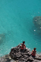 zwei frauen sitzen am felsen und schauen ins meer