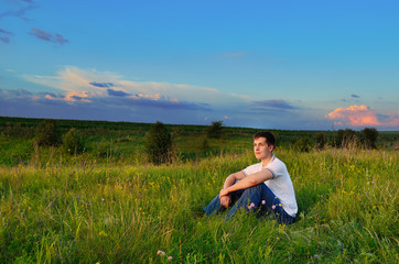 Naklejka na ściany i meble smiling young man on the hills with summer flowers