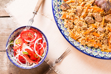 Pilaf and achichuk salad in handmade plate on wooden background