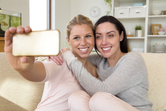 Same sex female couple taking a selfie using a mobile phone in their home