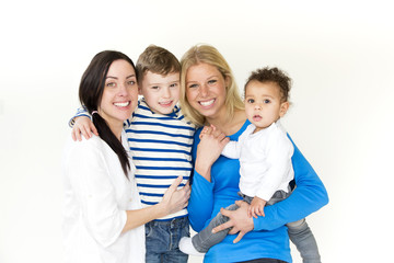 Same sex female couple posing with their two sons in front of a white background