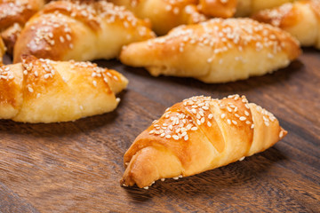 Mini croissants filled with cheese, with sesame on a wooden table