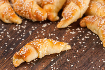 Mini croissants filled with cheese, with sesame on a wooden table