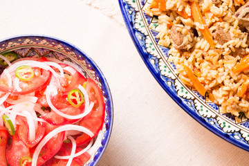 Pilaf and achichuk salad in handmade plate on wooden background