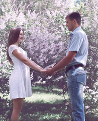 Fototapeta na wymiar Sweet young couple in love against the flowering spring garden
