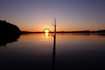 Sunset on a lake in Finland seen through a fishing rod ring on a warm and serene summer evening