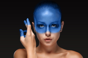 Portrait of a woman who is posing covered with blue paint