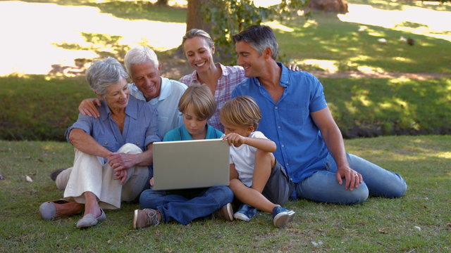 Happy family using laptop together in the park