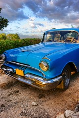 Old blue American classic car at sunset time in mountainous and green outdoor setting in Trinidad, Cuba