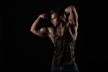 Fototapeta na wymiar Portrait of a handsome muscular bodybuilder posing over black ba