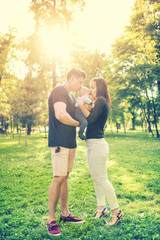 Happy familiy in park, mother and father holding and kissing a few months old son, kid. Infant portrait and happy family concept in park