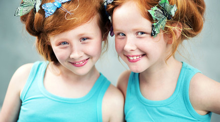 Smiling redhead sisters with butterfly in hair