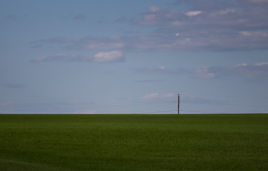Fototapeta na wymiar single pole on the horizon of field and sky
