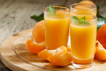 Fresh apricot juice and apricots with mint on wooden board, sele