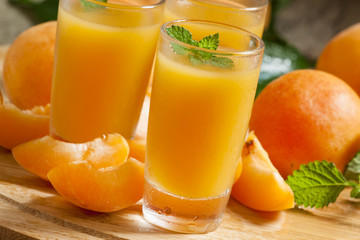 Fresh apricot juice and apricots with mint on wooden board, sele