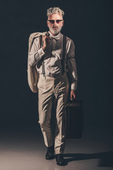 Stylish Senior Man Holding his Coat and Suitcase