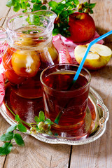 Drink with apple and wild roses on a wooden background