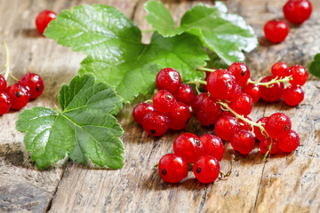 Red currants with leaves on old wooden background, selective foc