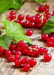Red currants with leaves on old wooden background, selective foc
