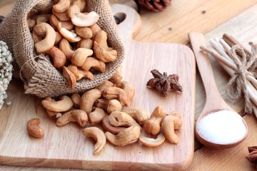 Fototapeta na wymiar Roasted cashews nuts with natural on wood background