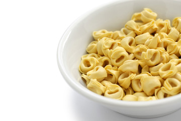 uncooked tortellini pasta in bowl isolated on white background