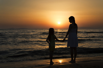 mother and daughter standing at sunset and looking at each other
