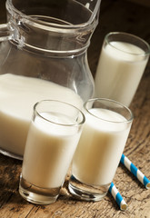 Jug of milk on old wooden table in rustic style, selective focus