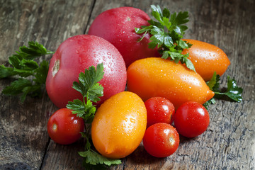 Assorted tomatoes: orange, pink, red cherry tomatoes with parsle