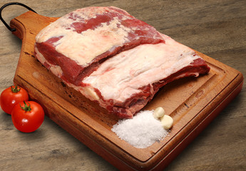 Raw meat selection on wooden cutting board with knife