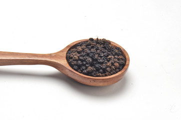Black pepper spices in wooden spoon