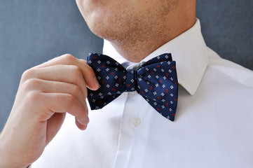 Man's hands touches bow-tie