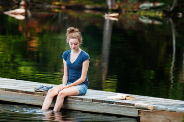 teenage girl sitting on a dock with her feet in the water