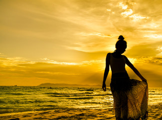 Portrait of young woman in dress as silhouette by the sea