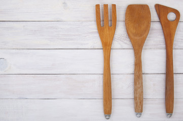 Wooden kitchen utensils on a background of white boards..