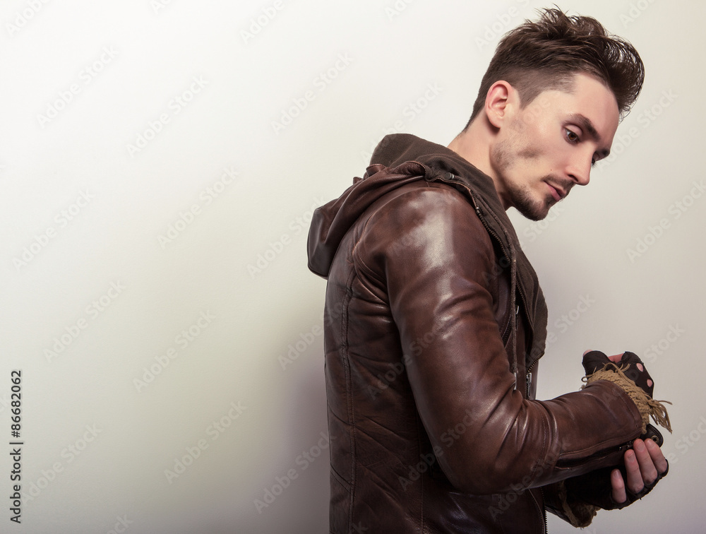 Wall mural attractive young man in a brown leather jacket pose in studio.