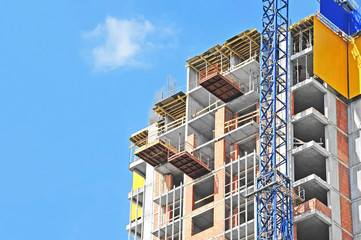 Crane and building construction site against blue sky