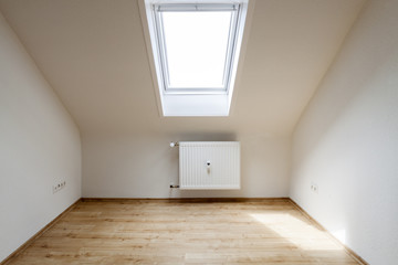 Empty attic room with roof skylight window