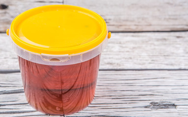Honey in a plastic bucket over rustic aged wooden background - 86687675