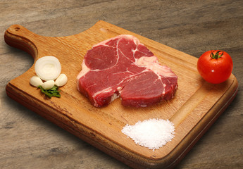 Raw meat selection on wooden cutting board with knife