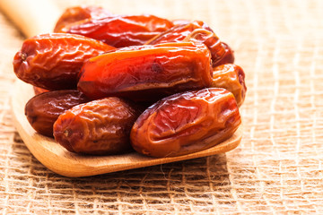 dried dates on wooden spoon cloth background