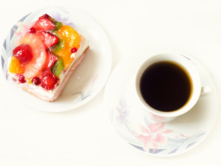 Yogurt dessert with fruits and berries in jelly and a cup of coffee on a white background